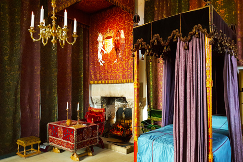 The sumptious Royal Apartments containing a four-poster bed and an ornate desk and chair in front of a fireplace