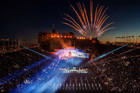 Fireworks next to floodlit Edinburgh Castle with audience, pipe bands and drummers at Edinburgh Tattoo