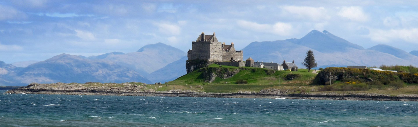 Cliff-top Duart Castle overlooking the Sound of Mull with mountains in the background