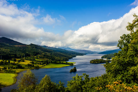 Trees, the clear water of Loch Tummel and blue sky with white clouds at Queen's View