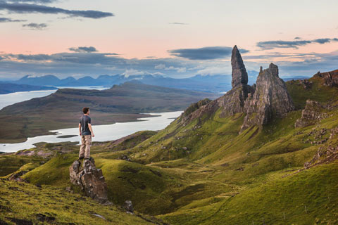 Man standing on small rock looking at the crags of the Old man of Storr on the Isle of Skye