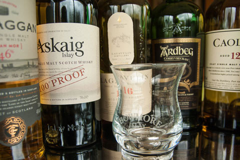 Close up of whisky glass with selection of Islay whisky bottles in background