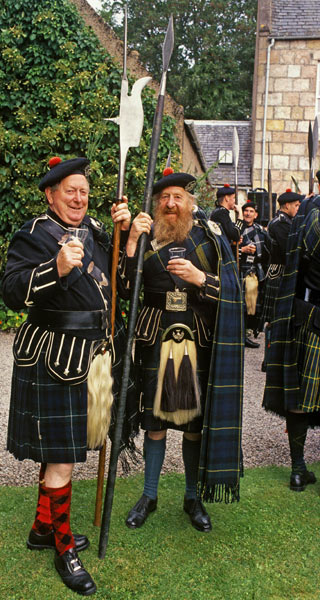 Men wearing sporrans, tartan kilts and cloaks holding large spears at a gathering