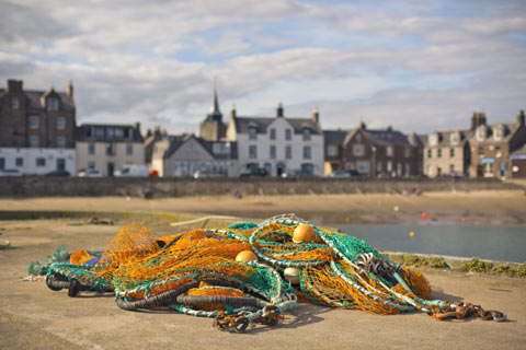 Bright green and yellow fishing net in foreground on a beach in an Aberdeenshire Fishing Village