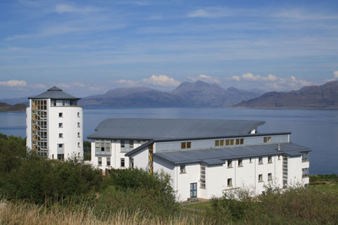 Modern white buildings comprising the Gaelic College on Skye with sea and mountains in background on a bright sunny day